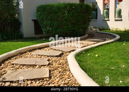 This unique photo of a beautiful curvy stone path through a meadow in a garden. the picture was taken in thailand Stock Photo