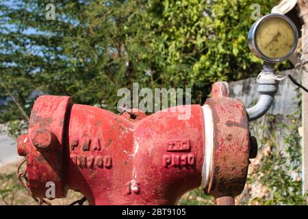 This unique photo shows an old red fire hydrant weathered by the tide with a pressure gauge on it. The picture was taken in Thailand Stock Photo