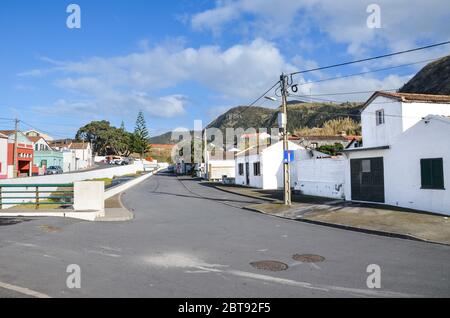 Mosteiros, Azores, Portugal - Jan 12, 2020: View of traditional Portuguese village in Azores Islands. Houses with white facades, asphalt road, power line. Horizontal photo. Stock Photo