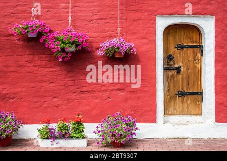 Old stone house decorated with colorful petunia flowers Facade house Stock Photo