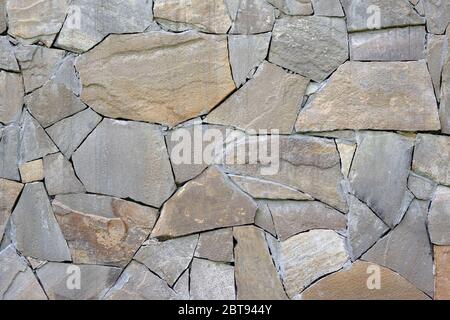Abstract gray stone background. Mosaic pattern of old brown stones on the facade of the house. Rock texture closeup. Masonry finish on the basement of Stock Photo