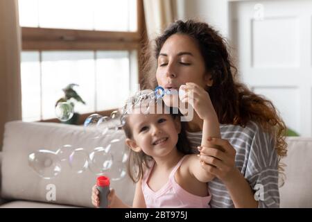 Close up mother blowing soap bubbles with little daughter Stock Photo