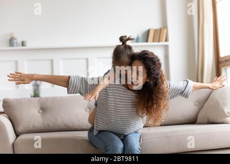 Laughing mother piggybacking little daughter, playing funny game