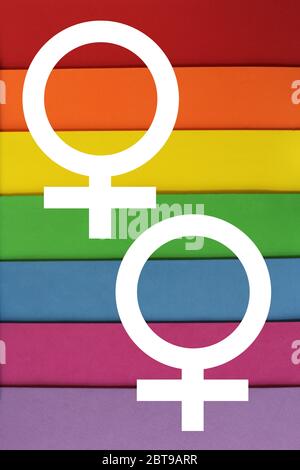 PHOTO of colourful paper in the colours of LGBT flag two white female symbols. Texture sheets of paper of red, orange, yellow, green, blue, purple. LGBT concept, symbol of LGBT, Background poster, Stock Photo