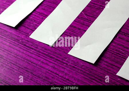Strips of white paper on a lilac background. Empty paper sheets on color wooden background. Creative background with scratches and scuffs. Training, b Stock Photo