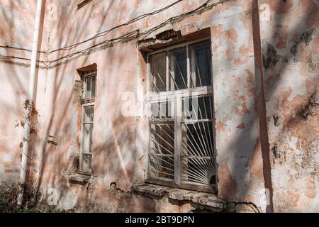 An old, crumbling window with a rusty bars on it. Damaged building. Stock Photo