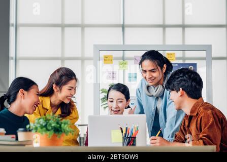 Asian woman boss thumbs up with ux developer and ui designer and looking at laptop screen for successful design approved at modern office.Creative dig Stock Photo