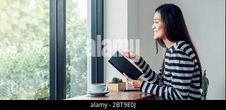 asian woman write plan to do list on notebook white listening music at home in quarantine time Stock Photo