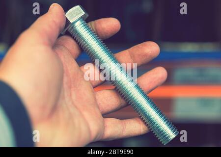 hand holds an iron bolt. repair concept. close-up. Stock Photo