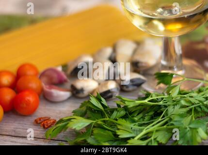 Ingredients for spaghetti alle vongole, an italian traditional recipe: spaghettis, clams, tomatoes, garlic, chilli, parsley and white wine Stock Photo