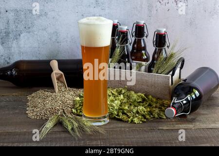 Craft wheat beer in high glass with wheat, hops and bottles. Stock Photo