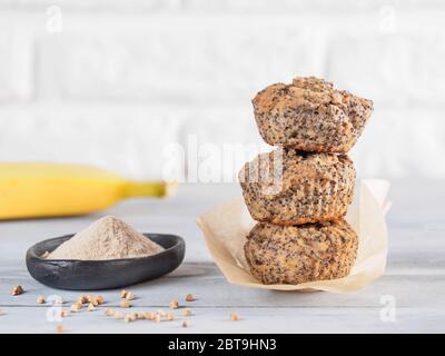 Healthy gluten-free homemmade banana muffins with buckwheat flour. Stack of three vegan muffins with poppy seeds on gray wooden table. Copy space Stock Photo