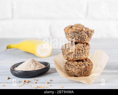 Healthy gluten-free homemmade banana muffins with buckwheat flour. Stack of three vegan muffins with poppy seeds on gray wooden table. Copy space Stock Photo