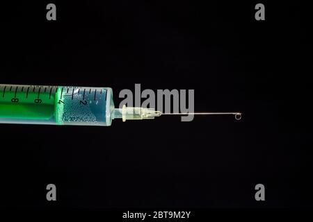 This photo illustration shows a disposable syringe with hypodermic needle, a black board behind Stock Photo