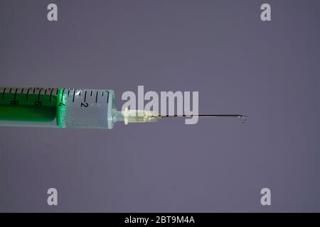 This photo illustration shows a disposable syringe with hypodermic needle, a grey board behind Stock Photo