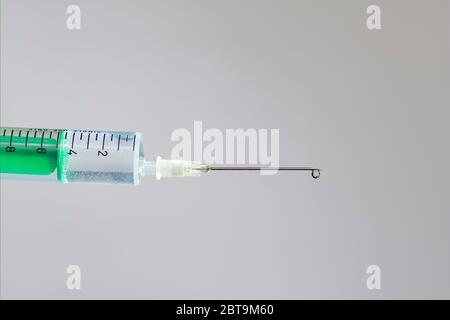 This photo illustration shows a disposable syringe with hypodermic needle, a white board behind Stock Photo