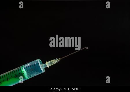 This photo illustration shows a disposable syringe with hypodermic needle, a black board behind Stock Photo