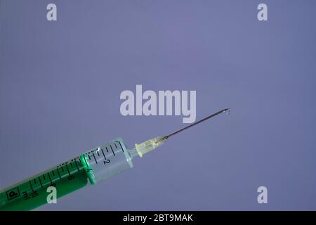 This photo illustration shows a disposable syringe with hypodermic needle, a grey board behind Stock Photo