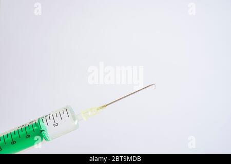 This photo illustration shows a disposable syringe with hypodermic needle, a white board behind Stock Photo