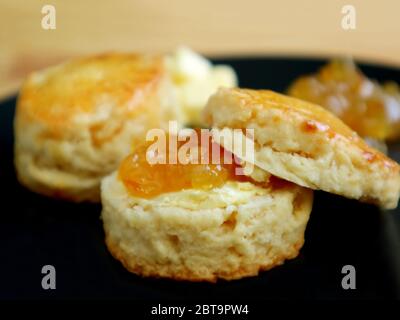 Closeup of Mouthwatering Candied Orange Zest Scones  with Marmalade Jam on a Black Plate Stock Photo