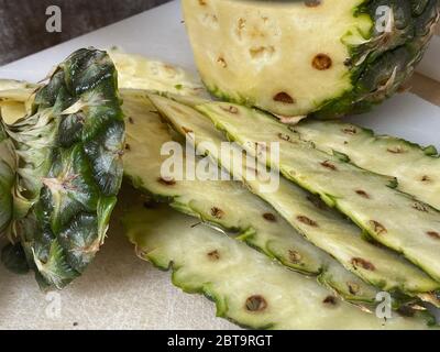 Large knife peeling whole pineapple on the desk in a kitchen Stock Photo