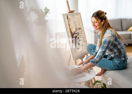 Art, creativity, hobby, job and creative occupation concept. Woman painting at home. Stock Photo