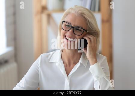 Smiling middle-aged woman have pleasant cell call Stock Photo