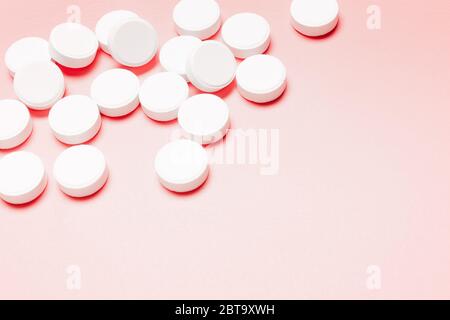 White, round pills on a pink background. The concept of the treatment of the disease, healthcare, women's health. Stock Photo