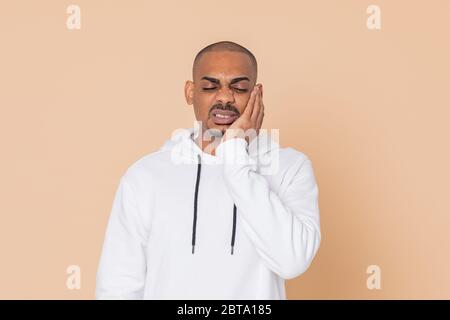 Pensive African guy with a white sweatshirt on a yellow background Stock Photo