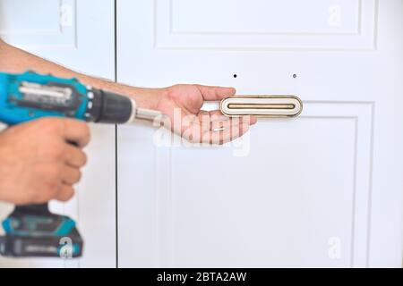 Installation of new cabinet, handyman sets door handles Stock Photo