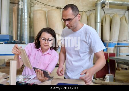 Male and female designers, carpenters, engineers working in an industrial workshop Stock Photo