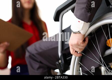 Man in suit on wheelchair communicates with woman Stock Photo