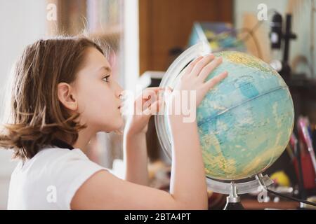 Young girl siiting at her desk and watching a globe.. Stock Photo