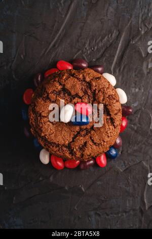 Homemade oat chocolate cookies stack with cereal with juicy jelly beans on textured dark black background, top view Stock Photo