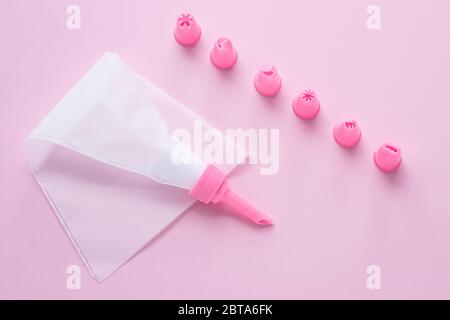 Cake decorating tools, the pastry bag with nozzles on pink background for cake decoration. Concept of cooking confectionery with cream Stock Photo