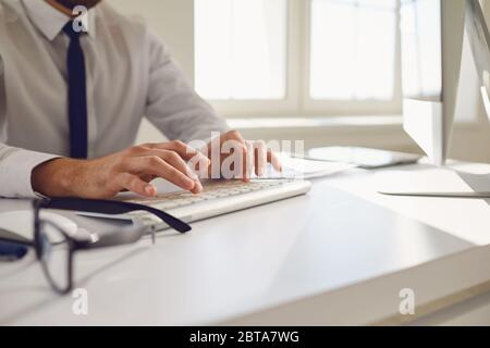 Busy faceless worker businessman is typing at workplace using computer in office.The work of the programmer blogger designer. Stock Photo