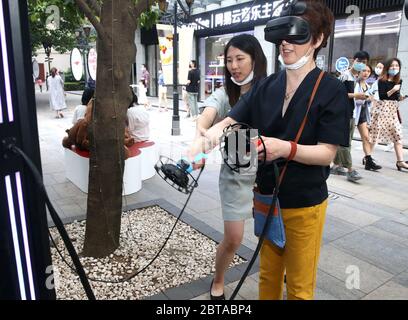 Shanghai, China. 24th May, 2020. A tourists experiences VR games at a night fair of Sinan Mansions in Shanghai, east China, May 24, 2020. A night fair of Sinan Mansions with food stalls, open air museum and art exhibitions etc., opened to boost Shanghai's nighttime economy. Credit: Chen Fei/Xinhua/Alamy Live News Stock Photo