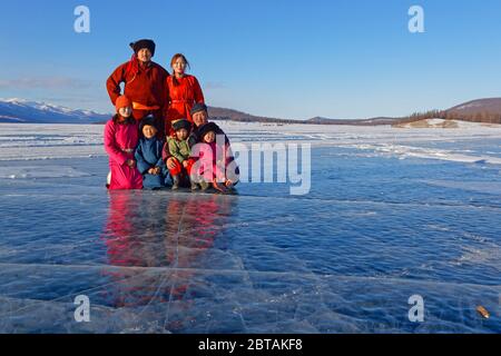 KHATGAL, MONGOLIA, March 2, 2020 : A mongolian family, dressed in traditional clothes, poses on the frozen lake. Stock Photo