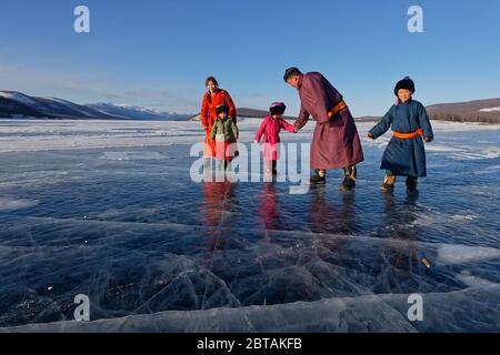 KHATGAL, MONGOLIA, March 2, 2020 : A mongolian family, dressed in traditional clothes, walks on the frozen lake. Stock Photo