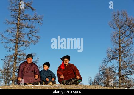 KHATGAL, MONGOLIA, March 2, 2020 : Mongolian people, dressed in traditional clothes, pose in a forest landscape. Stock Photo