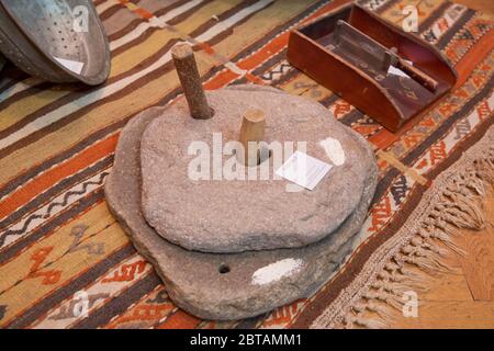Rotary discoid mill stone for hand-grinding a grain into flour. Medieval hand-driven millstone grinding wheat. The ancient Quern stone hand mill with Stock Photo
