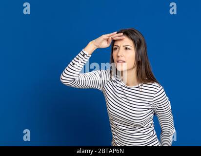 Brunette young woman wearing a striped T-shirt on a blue background Stock Photo