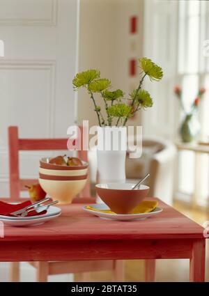 Vase of lime green chrysanthemums on pink dining table Stock Photo