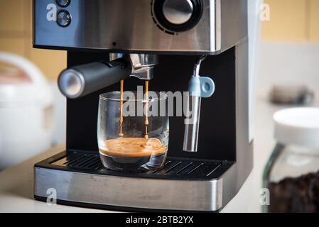 Espresso brewing from a coffee maker in a glass closeup Stock Photo