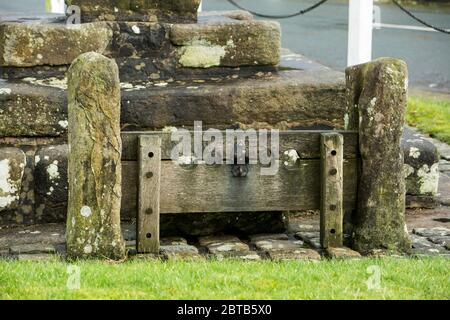 Old stocks and the stump of a cross on the village green at Bolton-by-Bowland in the Forest of Bowland, Lancashire Stock Photo