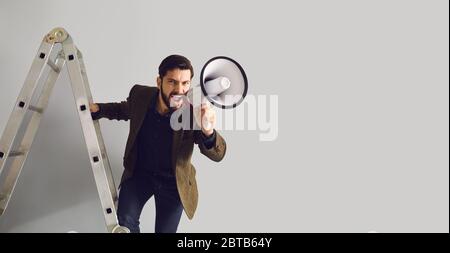 Businessman on the stairs with a megaphone in hand shouts Stock Photo