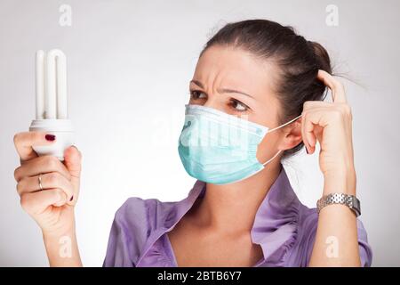 Young woman holding a light bulb while wearing a mask Stock Photo