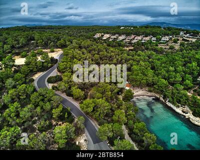Aerial photography cove with green lagoon turquoise water, hillside houses in small village of Banyalbufar, mountain winding road, Majorca, Spain Stock Photo