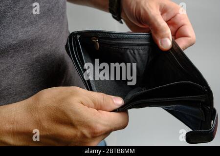 Man looks at an empty purse without money.There is no money crisis Stock Photo