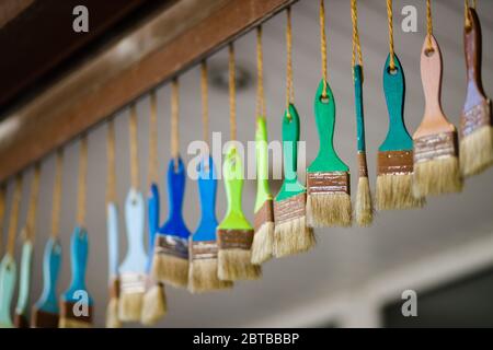 Many colorful brushes hang on ropes close view Stock Photo